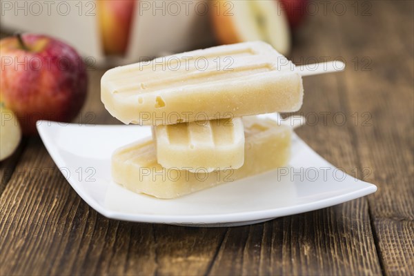 Vintage wooden table with Apple Popsicles (close-up shot, selective focus)