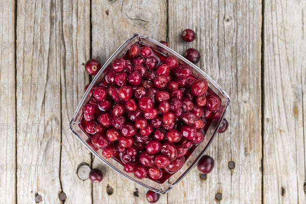 Old wooden table with fresh Preserved Cranberries (close-up shot, selective focus)