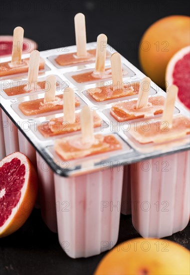 Some freshly made Grapefruit Popsicles (with some fresh fruits, selective focus)