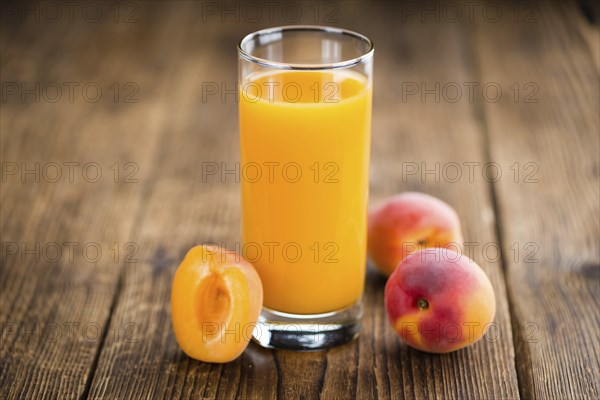 Fresh made Apricot Juice on a vintage background (close-up shot)
