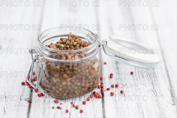 Preserved Pink Peppercorns on an old wooden table as detailed close-up shot, selective focus