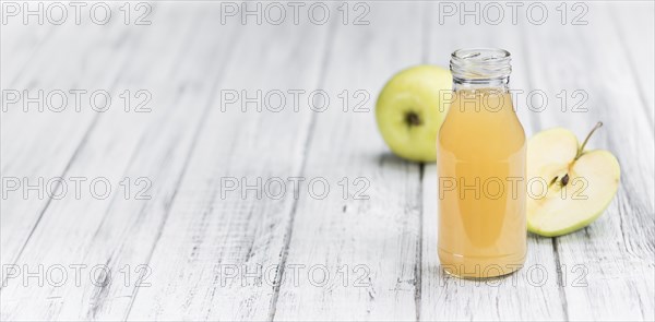 Homemade Apple Juice on an wooden table (selective focus) as detailed close-up shot