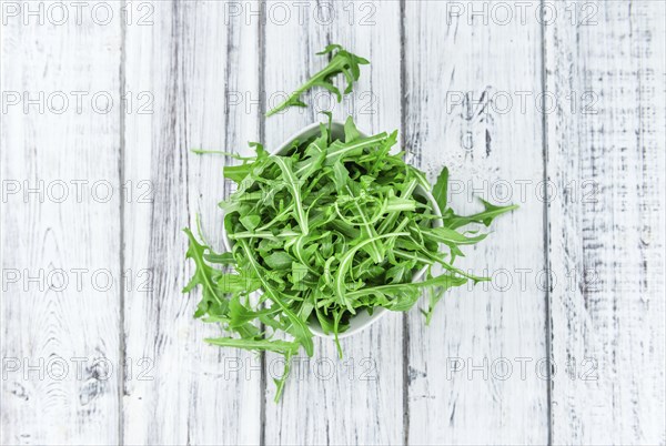 Fresh Arugula on an old wooden table as detailed close-up shot