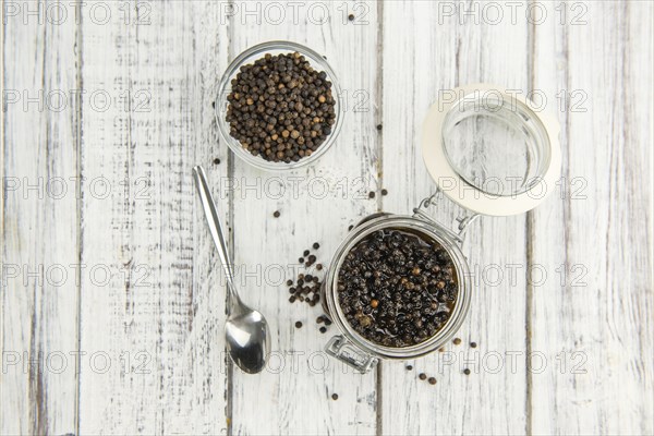 Black Peppercorns preserved on wooden background, selective focus, close-up shot