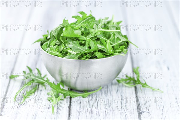 Wooden table with fresh Arugula as detailed close-up shot (selective focus)