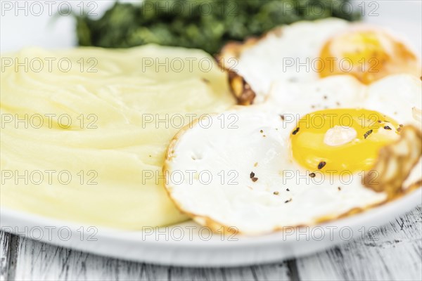 Some homemade Mash (selective focus) as detailed close-up shotwith fried eggs and spinach