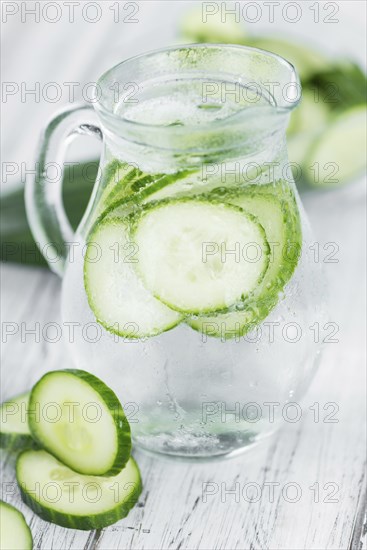 Fresh made Cucumber Water as high detailed close-up shot on a vintage wooden table, selective focus