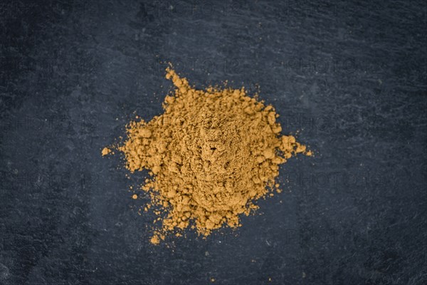 Portion of Cinnamon Powder on a rustic slate slab (selective focus, close-up shot)