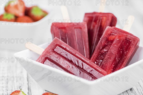 Strawberry Popsicles (close-up shot, selective focus) on a rustic background