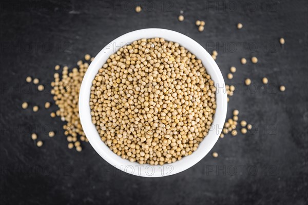 Portion of Mustard Seeds as detailed close up shot on a slate slab (selective focus)
