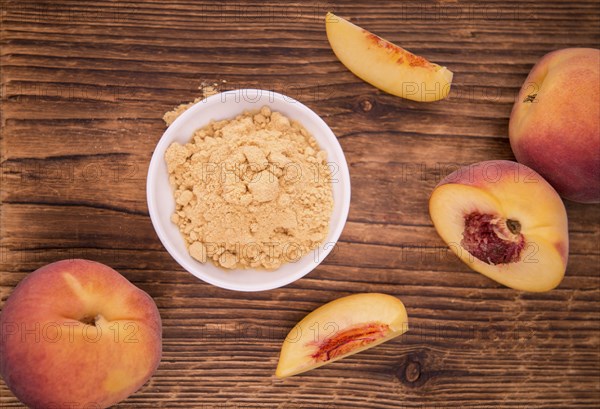 Ground Peaches as high detailed close-up shot on a vintage wooden table, selective focus