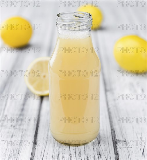 Homemade Lemon Juice on an wooden table (selective focus) as detailed close-up shot