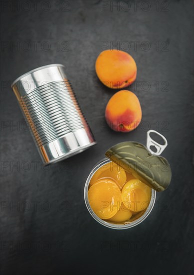 Portion of Canned Apricots as detailed close up shot on a slate slab (selective focus)