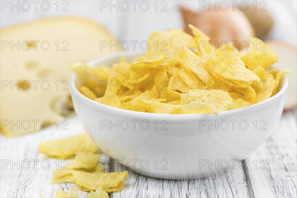Homemade Cheese and Onion Potato Chips on vintage background (selective focus, close-up shot)