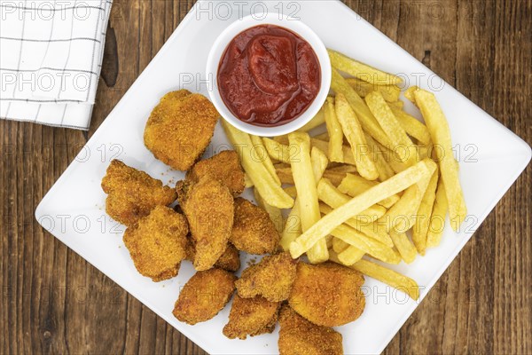 Vintage wooden table with fresh made Chicken Nuggets (close-up shot, selective focus)