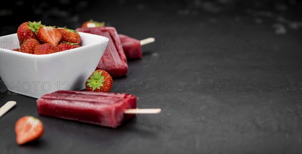 Slate slab with homemade Strawberry Popsicles (selective focus, close-up shot)