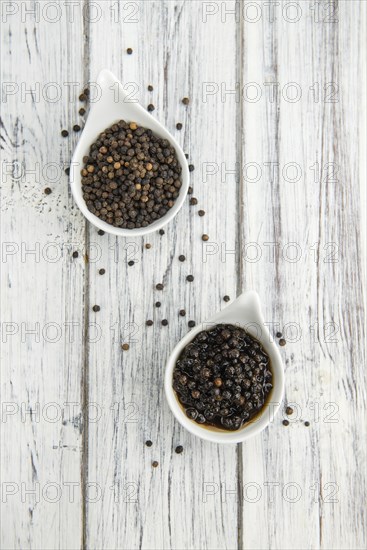 Black Peppercorns preserved on wooden background, selective focus, close-up shot
