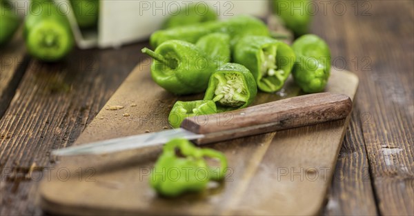 Raw Pimientos on an old wooden table as detailed close-up shot, selective focus