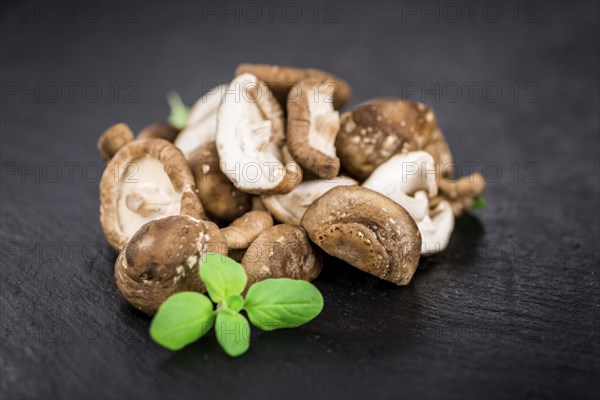 Portion of Shiitake mushrooms as detailed close up shot on a slate slab, selective focus