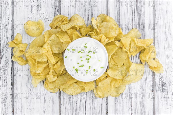 Potato Chips (Sour Cream taste) on a vintage background as detailed close-up shot (selective focus)