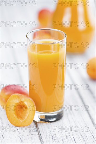 Fresh made Apricot Juice on a vintage background (close-up shot)
