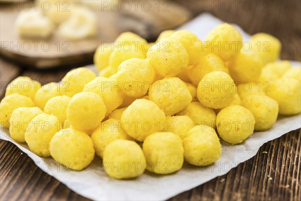 Cheese Balls on an old wooden table as detailed close-up shot (selective focus)