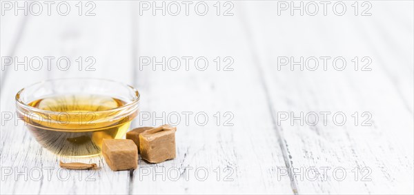 Caramel Syrup as high detailed close-up shot on a vintage wooden table (selective focus)