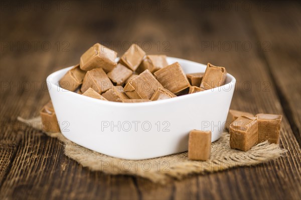 Caramel pieces as high detailed close-up shot on a vintage wooden table (selective focus)