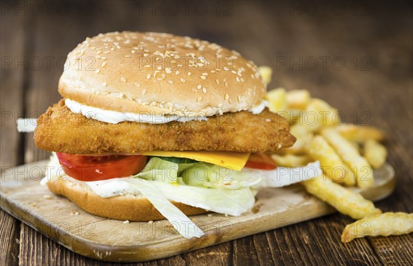 Homemade Fish Burger (close-up shot, selective focus) on a wooden table