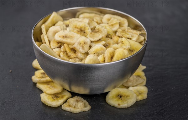 Portion of Dried Banana Chips on a rustic slate slab, selective focus, close-up shot