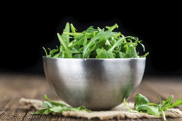 Wooden table with fresh Arugula as detailed close-up shot (selective focus)