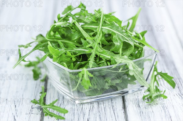 Wooden table with fresh Arugula as detailed close-up shot (selective focus)