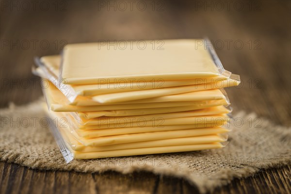Cheese (sliced) on an old wooden table as detailed close-up shot (selective focus)
