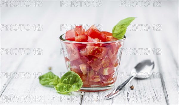Tomatoes (diced) as high detailed close-up shot on a vintage wooden table (selective focus)