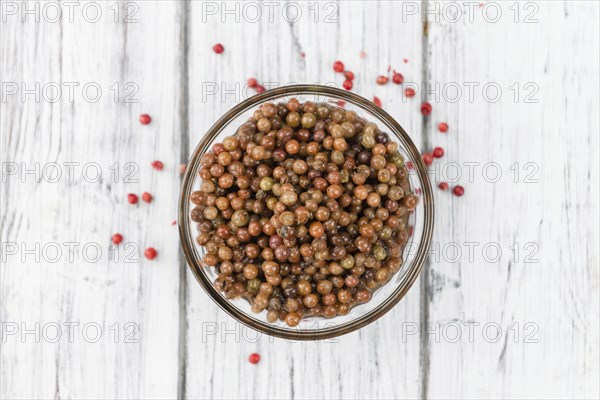 Fresh made Pink Peppercorns (preserved) on an old and rustic wooden table, selective focus,