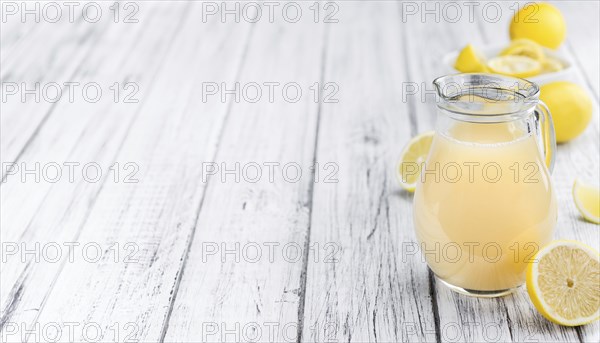 Fresh made Juice (lemon) on an old and rustic wooden table (selective focus, close-up shot)