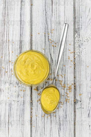 Fresh made Mustard on a vintage background (close-up shot)