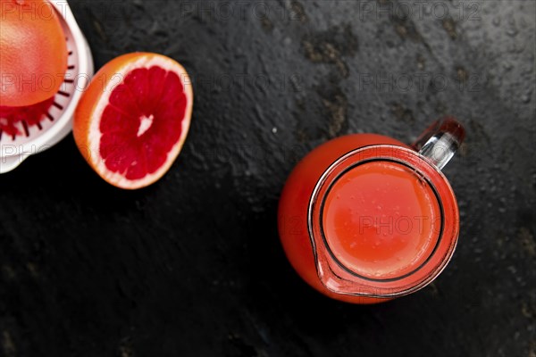 Some freshly squeezed Grapefruit Juice on a vintage background (close-up shot, selective focus)
