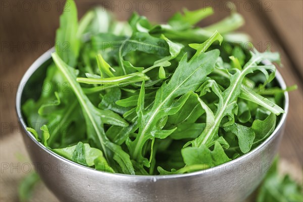 Fresh Arugula on an old wooden table as detailed close-up shot