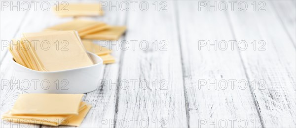 Cheese (sliced) on an old wooden table as detailed close-up shot (selective focus)