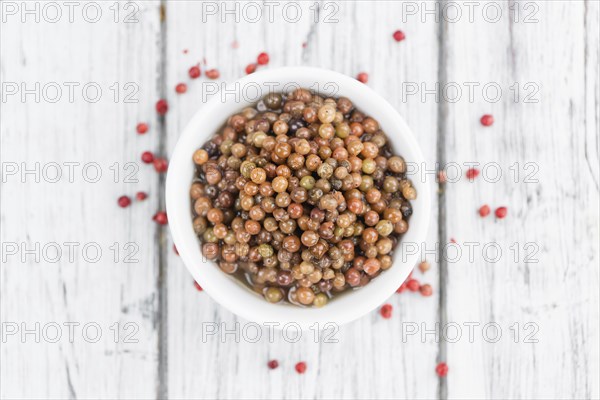 Preserved Pink Peppercorns on a vintage background as detailed close-up shot, selective focus