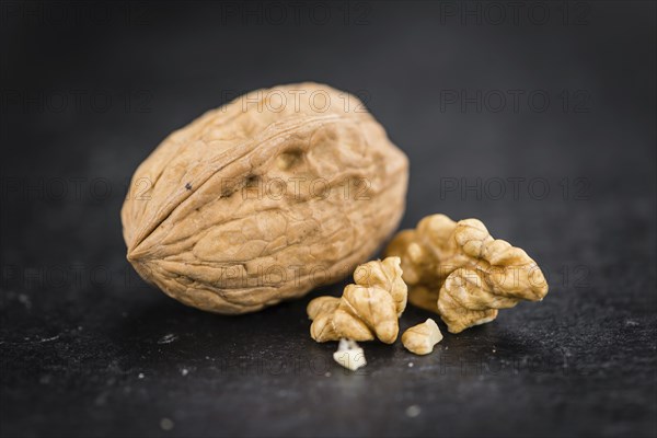 Portion of Whole Walnuts on a rustic slate slab (selective focus, close-up shot)