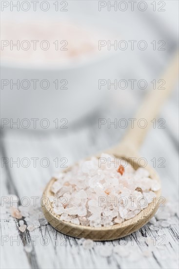 Salt (pink) on an old wooden table as detailed close-up shot (selective focus)