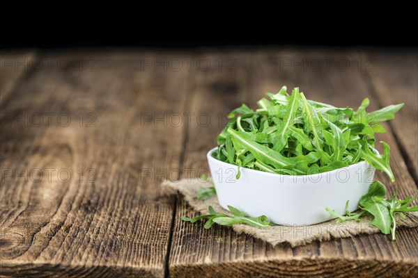 Fresh Arugula (selective focus) as detailed close-up shot on vintage background