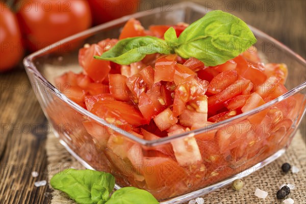 Tomatoes (diced) as high detailed close-up shot on a vintage wooden table (selective focus)