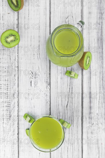 Wooden table with fresh made Kiwi Smoothie (close-up shot, selective focus)