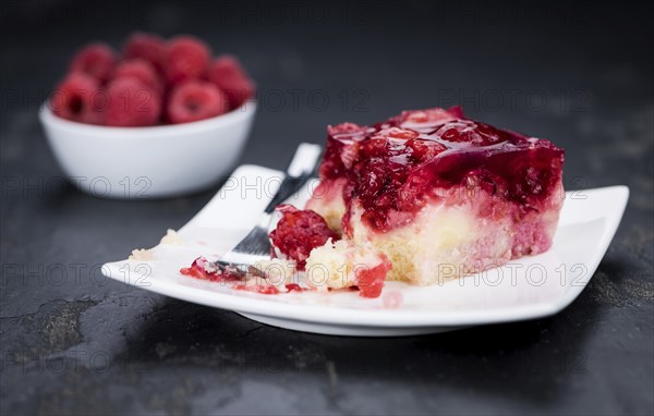 Fresh made portion of Raspberry Cake (selective focus, close-up shot) on rustic background