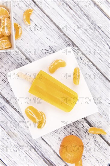 Portion of fresh homemade Tangerine Popsicles (close-up shot, selective focus) on a vintage