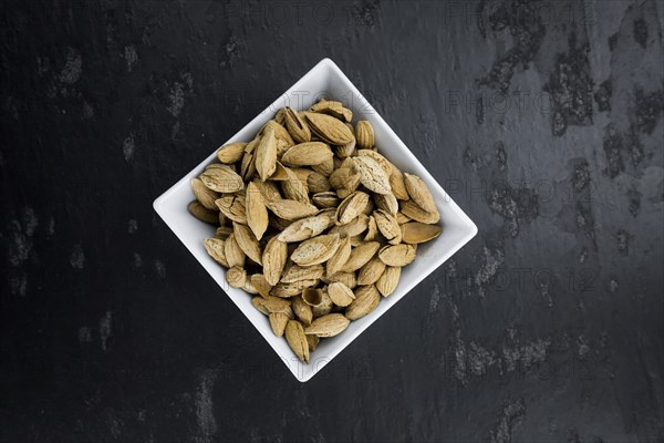 Almonds in shell (roasted and salted) on a vintage background (close-up shot)