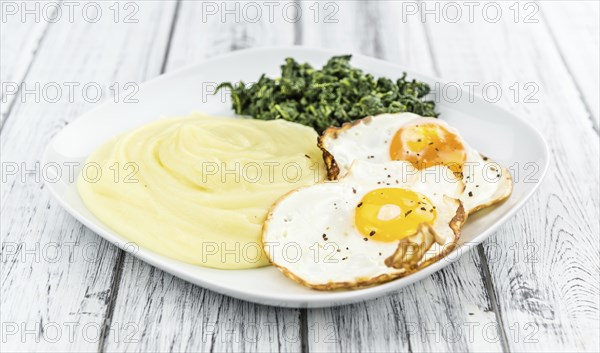 Some homemade Mash (selective focus) as detailed close-up shotwith fried eggs and spinach